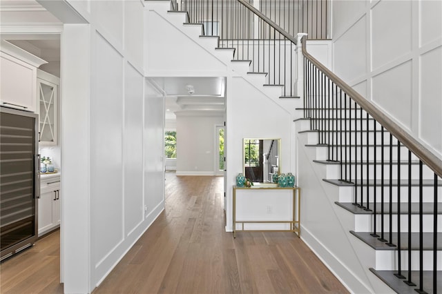 foyer entrance with wood finished floors, baseboards, a high ceiling, stairs, and a decorative wall