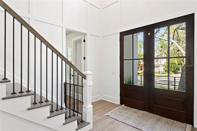 entryway featuring french doors, wood finished floors, stairs, and a decorative wall