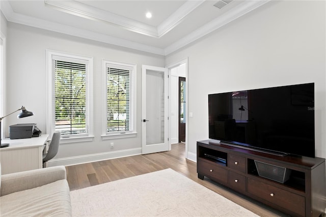 living area featuring a tray ceiling, wood finished floors, baseboards, and ornamental molding