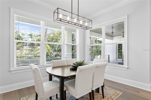 dining area with a notable chandelier, crown molding, baseboards, and wood finished floors