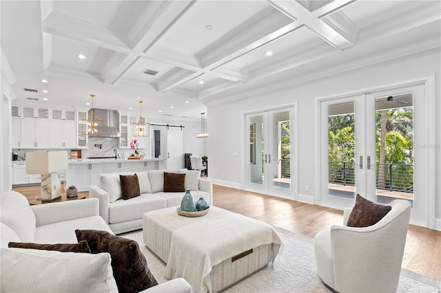 living area featuring a barn door, beamed ceiling, french doors, and light wood-style floors