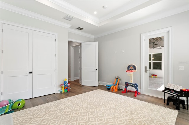 rec room featuring visible vents, ornamental molding, wood finished floors, baseboards, and a raised ceiling