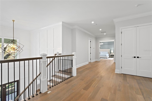 hall featuring baseboards, ornamental molding, an upstairs landing, an inviting chandelier, and wood finished floors