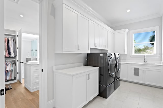 laundry area with a sink, cabinet space, ornamental molding, and washer and clothes dryer