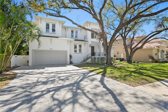 view of front of property featuring stucco siding, a front lawn, decorative driveway, fence, and an attached garage