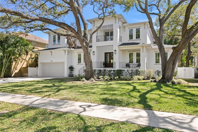 view of front of property featuring stucco siding, a front lawn, driveway, fence, and a balcony