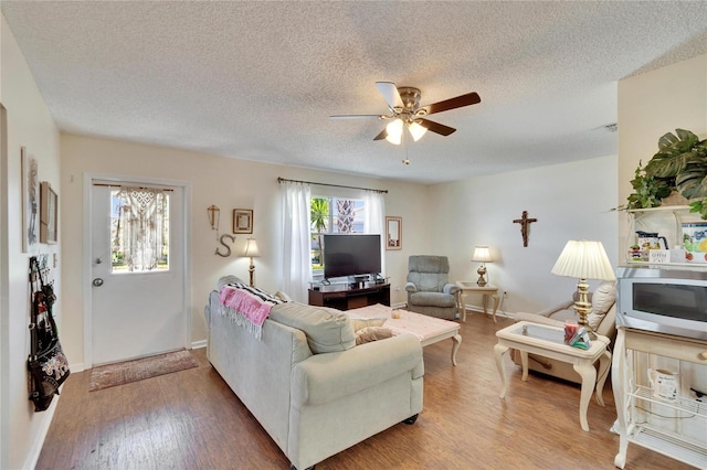 living room with baseboards, a ceiling fan, a textured ceiling, and wood finished floors
