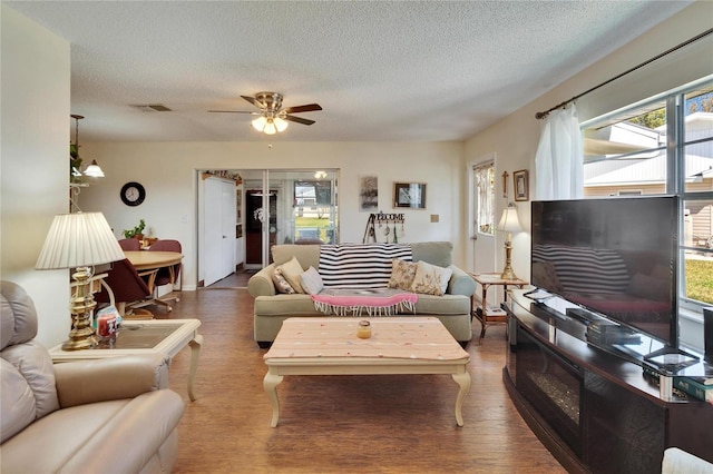 living room with visible vents, a textured ceiling, ceiling fan, and wood finished floors