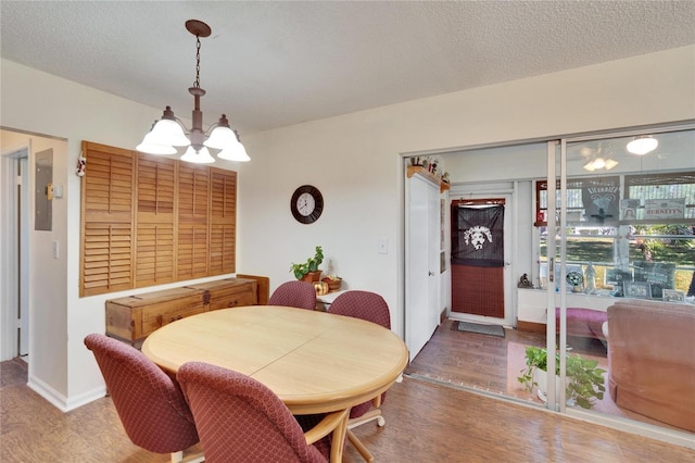 dining area featuring baseboards, a textured ceiling, an inviting chandelier, and wood finished floors