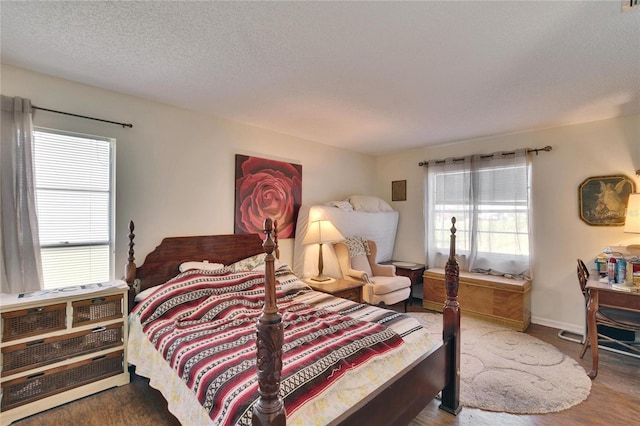 bedroom featuring baseboards, a textured ceiling, and wood finished floors