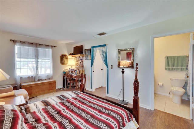 bedroom with ensuite bathroom, baseboards, and visible vents