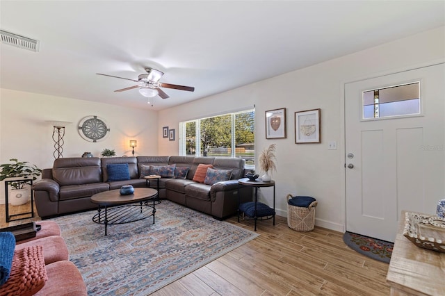 living area featuring light wood-type flooring, baseboards, visible vents, and a ceiling fan