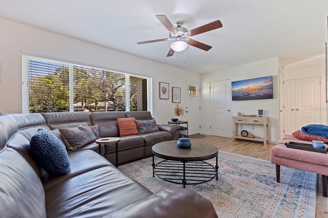 living area with baseboards, ceiling fan, and light wood finished floors