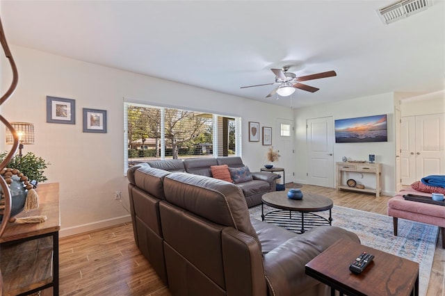 living room with visible vents, light wood-style flooring, baseboards, and ceiling fan