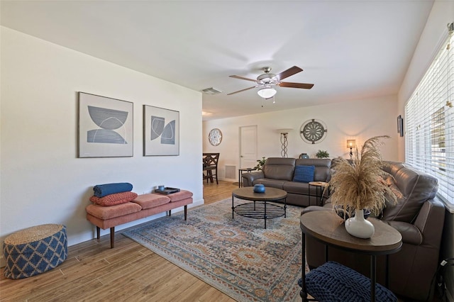 living room featuring visible vents, baseboards, a ceiling fan, and wood finished floors