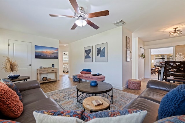 living room with visible vents, baseboards, wood finished floors, and a ceiling fan