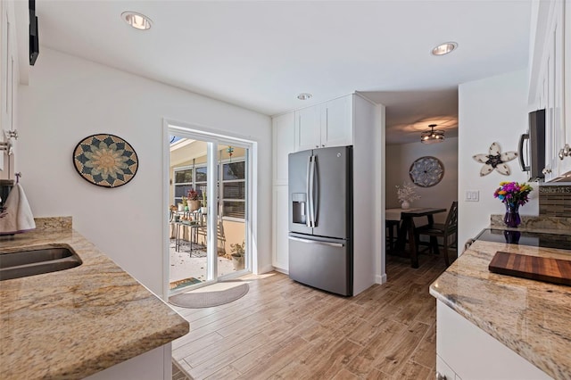 kitchen with light stone counters, light wood finished floors, recessed lighting, appliances with stainless steel finishes, and white cabinetry