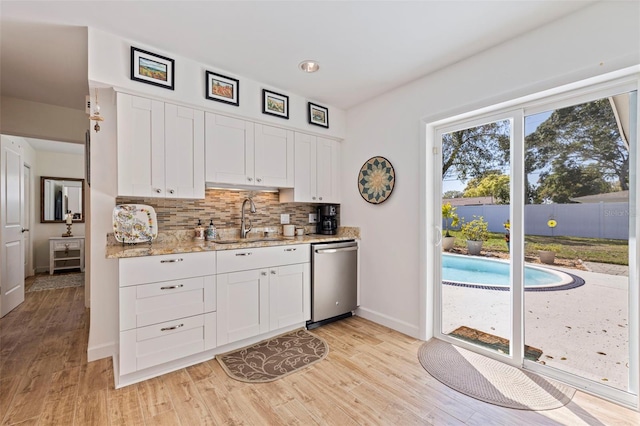 kitchen with backsplash, a sink, white cabinets, and stainless steel dishwasher