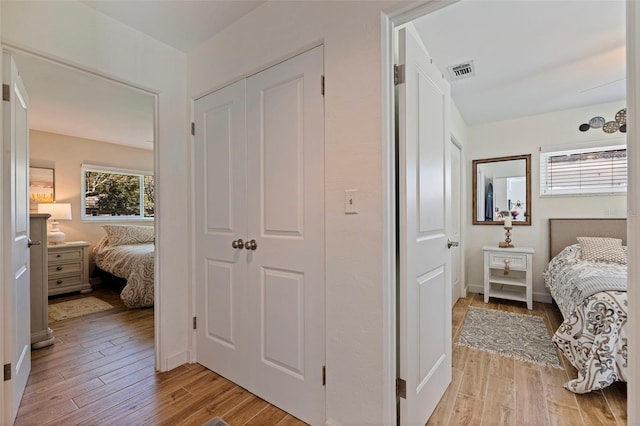 bedroom featuring light wood finished floors, visible vents, and a closet