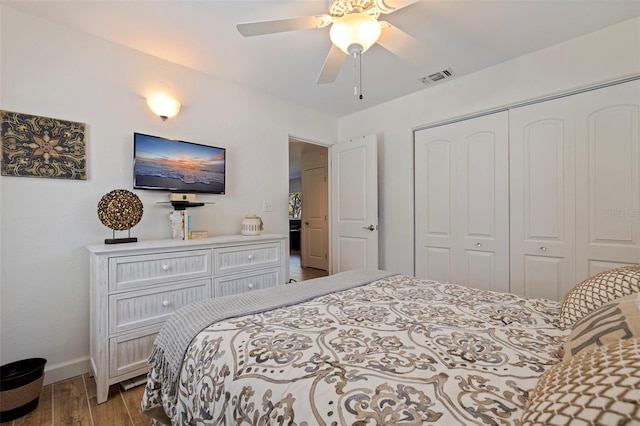 bedroom featuring wood finished floors, visible vents, baseboards, ceiling fan, and a closet