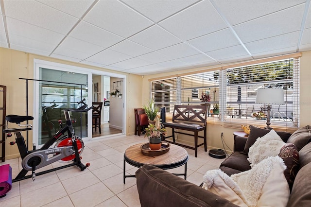 tiled living area featuring a drop ceiling and baseboards