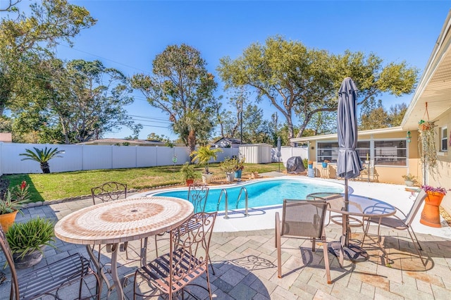 view of pool featuring a storage unit, a patio, a fenced backyard, a yard, and a fenced in pool