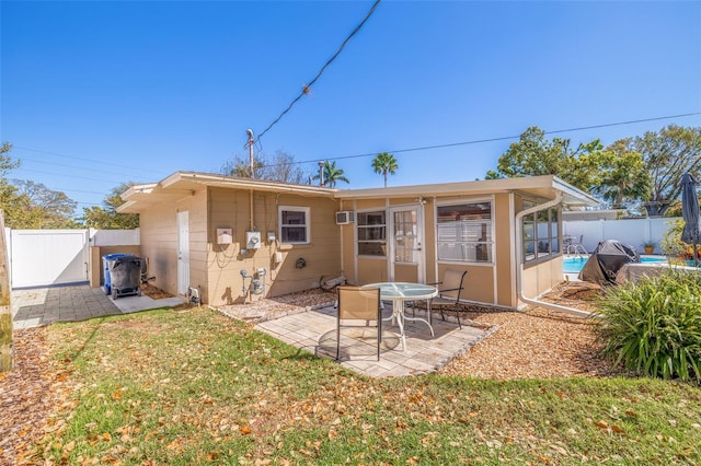 rear view of property featuring an AC wall unit, a gate, a fenced backyard, a yard, and a patio area