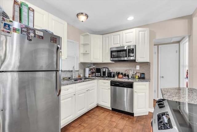 kitchen with a sink, light wood-style floors, stainless steel appliances, white cabinetry, and tasteful backsplash