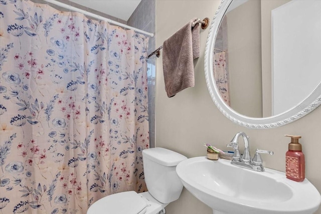 bathroom featuring a sink, a shower with shower curtain, and toilet