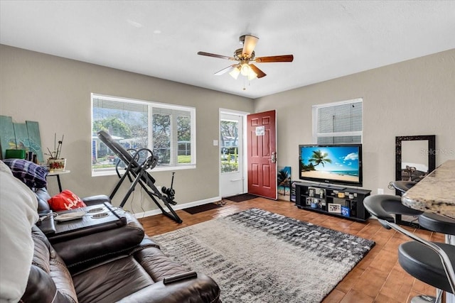 living room featuring baseboards, a ceiling fan, and wood finished floors