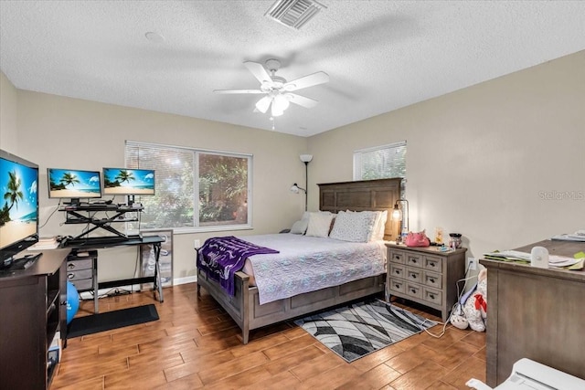 bedroom featuring visible vents, baseboards, a textured ceiling, and wood finished floors