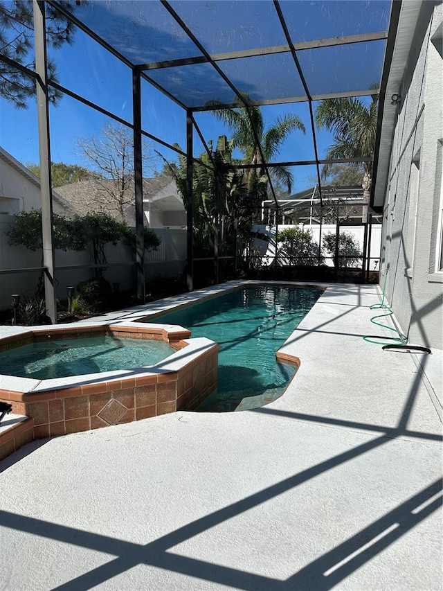 view of pool featuring glass enclosure, a pool with connected hot tub, and a patio area