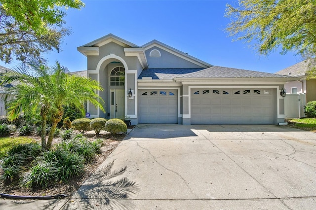 view of front of property featuring a shingled roof, concrete driveway, an attached garage, and stucco siding