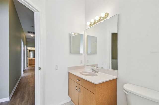 bathroom featuring vanity, wood finished floors, visible vents, baseboards, and toilet