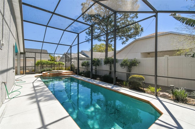 view of pool featuring a patio area, glass enclosure, a pool with connected hot tub, and fence