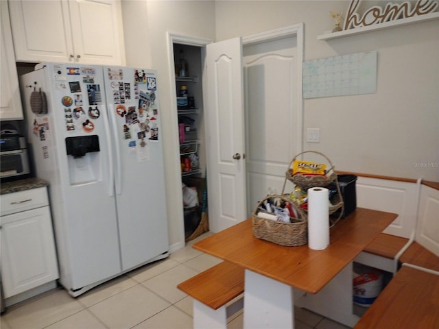 kitchen with white cabinets, light tile patterned flooring, and white fridge with ice dispenser