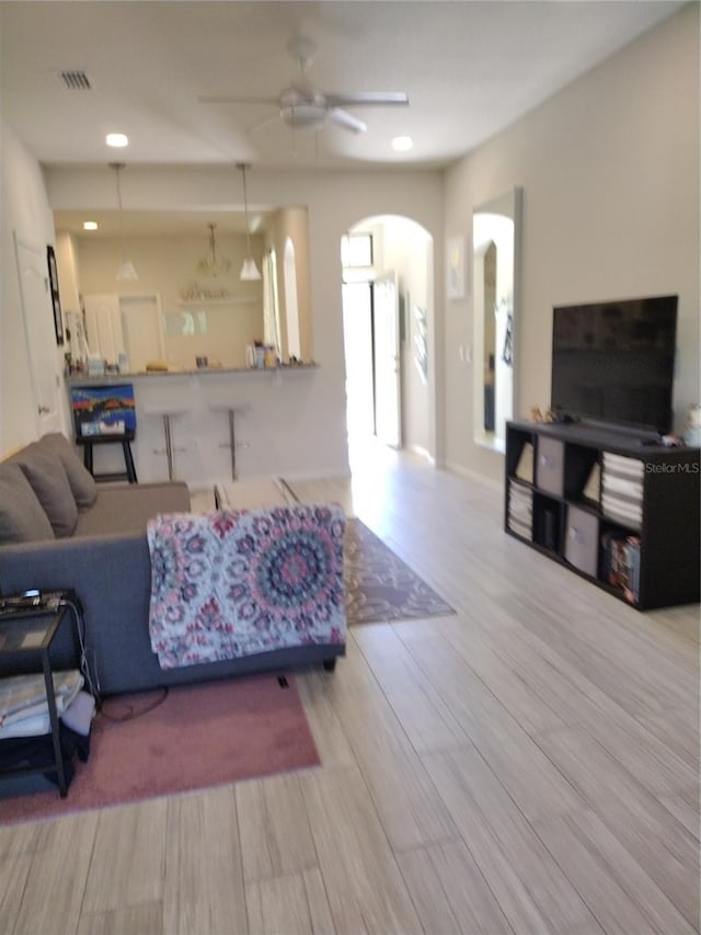 living room with visible vents, recessed lighting, wood finished floors, arched walkways, and a ceiling fan