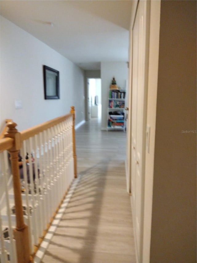 hall featuring an upstairs landing and light wood-type flooring