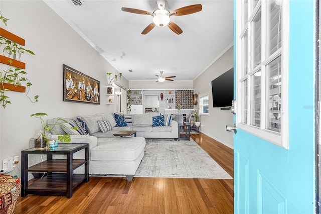 living room featuring crown molding, wood finished floors, and ceiling fan