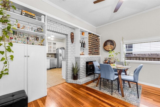 dining area featuring crown molding, a ceiling fan, light wood-style floors, and a textured ceiling