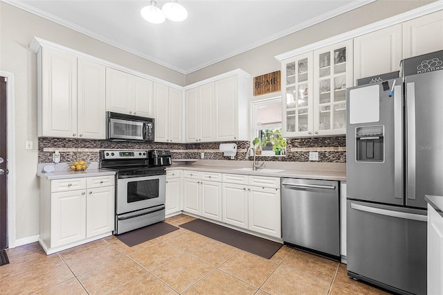 kitchen with ornamental molding, appliances with stainless steel finishes, white cabinets, light tile patterned floors, and decorative backsplash