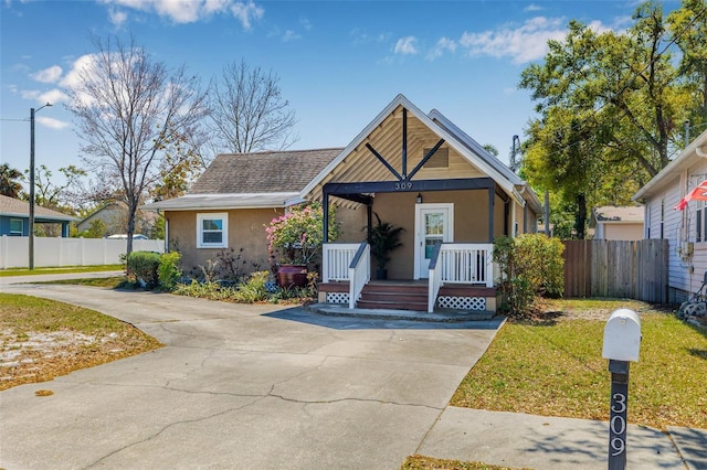 view of front of property with covered porch, concrete driveway, fence, and stucco siding