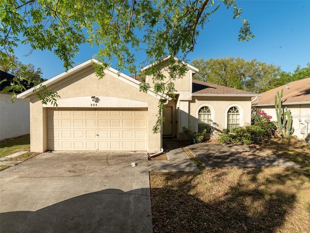 mediterranean / spanish house with stucco siding, a garage, driveway, and a shingled roof