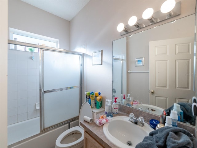 bathroom with toilet, vanity, and bath / shower combo with glass door