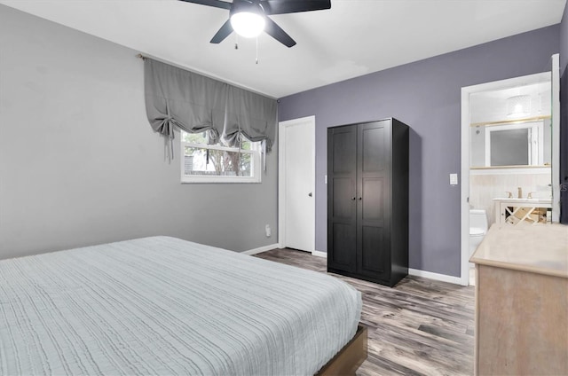 bedroom featuring baseboards, a ceiling fan, wood finished floors, and ensuite bathroom