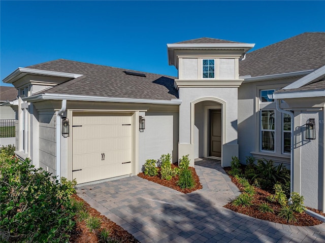 view of front of home featuring driveway, a garage, roof with shingles, and stucco siding