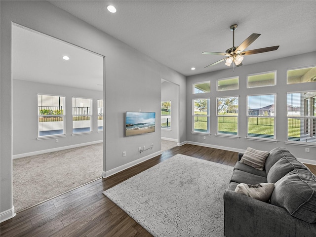 living room featuring plenty of natural light, a ceiling fan, dark wood-style flooring, and baseboards