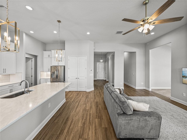 kitchen featuring visible vents, a sink, white cabinets, stainless steel fridge, and dark wood-style flooring