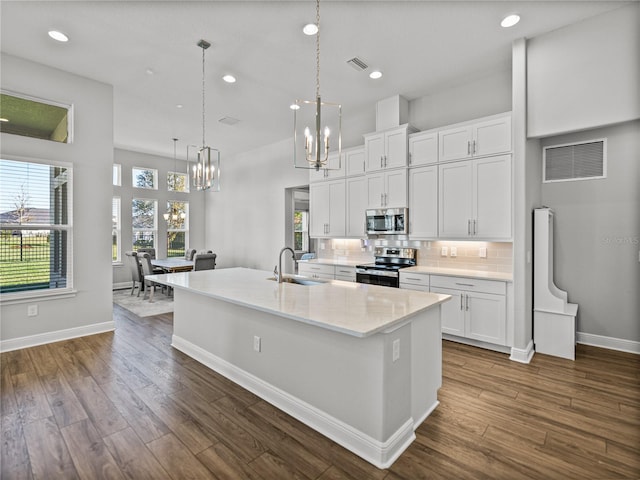 kitchen with visible vents, a chandelier, decorative backsplash, appliances with stainless steel finishes, and a sink