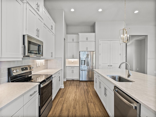 kitchen featuring dark wood-type flooring, a chandelier, decorative backsplash, stainless steel appliances, and a sink